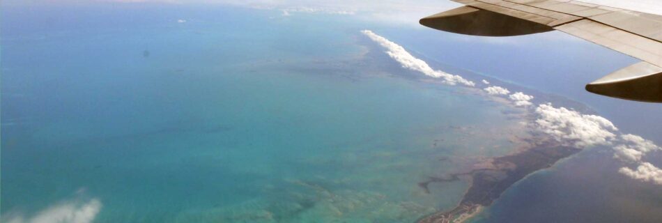 Airplane wing over ocean and island